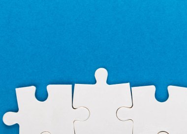 Mavi arka planda beyaz yapboz parçaları. Metin için alanı olan bir desen fotoğrafı. Takım çalışması kavramsal fotoğraf.