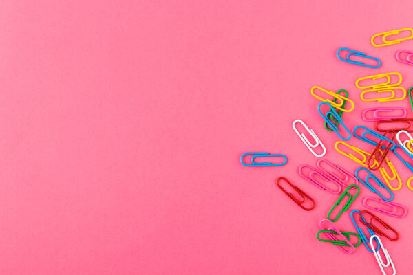 Colored paper clips. Colored paper clips macro close up isolated on a pink background with copy space.