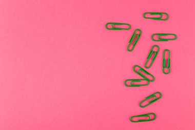 Renkli ataçlar. Yeşil kağıt ataçları makroyu kapatın. Pembe bir arkaplanda kopyalama alanı ile izole edilmiş..