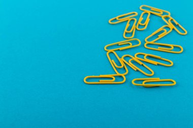 Renkli ataçlar. Sarı kağıt ataçları makroyu kapatır mavi arkaplanda kopyalama alanı ile izole edilir.