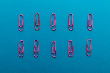 Renkli ataçlar. Pembe kağıt ataçları makroyu kapatır mavi bir arkaplanda kopyalama alanı ile izole edilir.