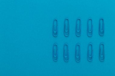 Renkli ataçlar. Mavi kağıt ataçları makroyu kapatın. Kopyalama alanı olan mavi bir arkaplanda izole edilmiş..