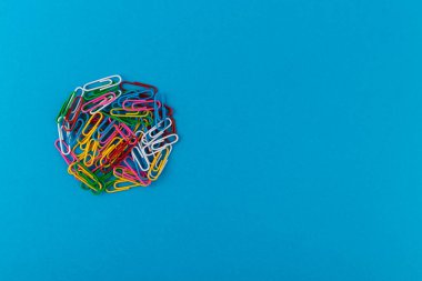 Renkli ataç çemberi. Renkli ataçlar makro, mavi bir arkaplanda kopyalama alanı ile izole edilmiş olarak kapat.