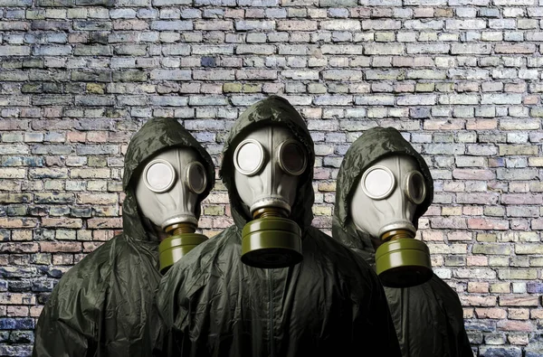 Gasmaskers Drie Mensen Met Gasmaskers Bakstenen Muur Achter Met Kopieerruimte — Stockfoto