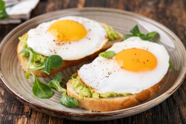 Tahta bir masada kızarmış yumurtalı tost.