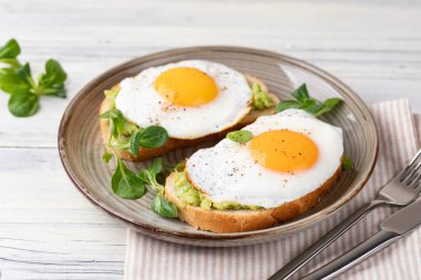 Tahta bir masada kızarmış yumurtalı tost.