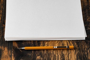 Tahta masanın üzerinde mekanik kalemle boş bir kağıt.