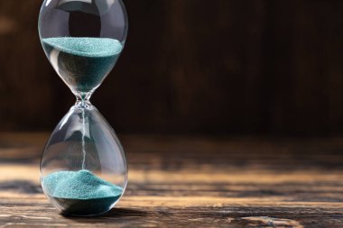 Kum saatinin seçmeli odak noktası ve ahşap arka planda yeşil kum
