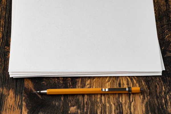 Tahta masanın üzerinde mekanik kalemle boş bir kağıt.