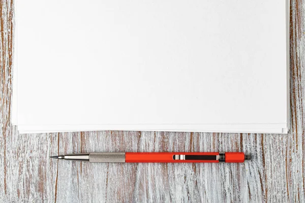 Tahta masanın üzerinde mekanik kalemle boş bir kağıt.