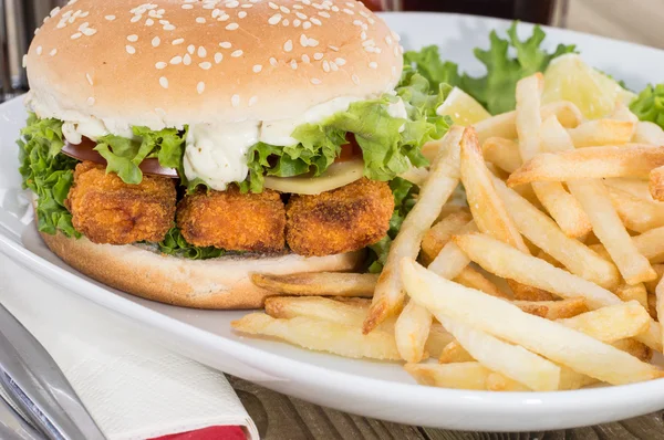 Burger au poisson avec des chips sur une assiette — Photo