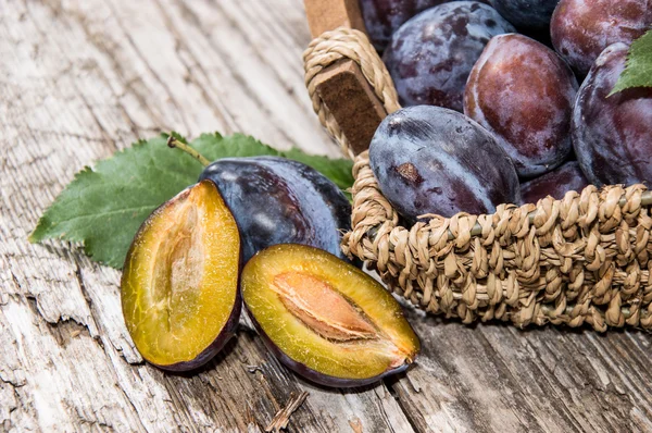 Algunas ciruelas delante de una canasta — Foto de Stock