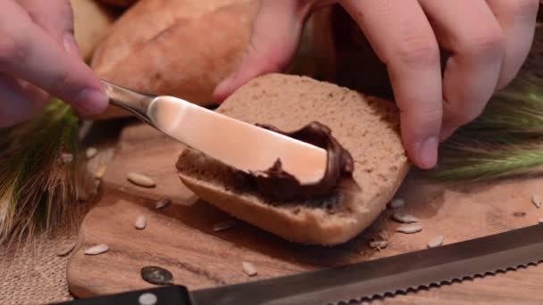 Schokoladencreme auf ein Brötchen geben — Stockvideo