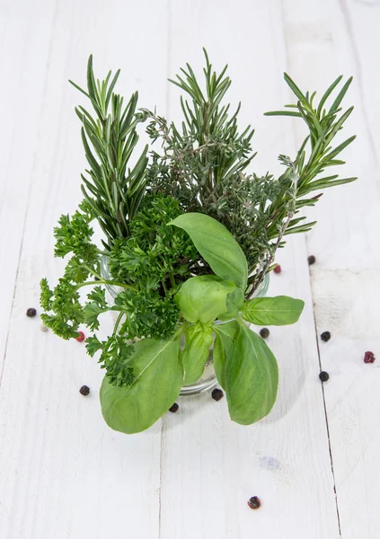 Glass with herbs on white painted wood — Stock Photo, Image