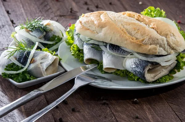 Arenque Filet em uma baguete (contra a madeira ) — Fotografia de Stock