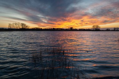 Gölün üzerinde bulutlar olan renkli günbatımı
