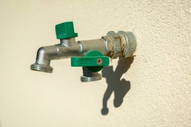 Parlak duvarda çifte pirinç bahçe musluğu var.