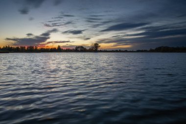 Akşam gökyüzü ve bulutlar sakin bir göl üzerinde, Stankow, Polonya