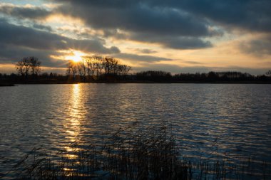 Sakin bir göl üzerinde bulutlarla gün batımı, Stankow, Polonya