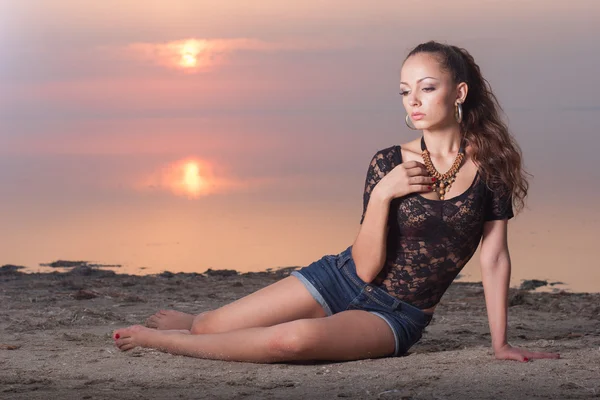 夕暮れ時のビーチの短いジーンズでセクシーな美しい女性 ストック写真