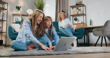 Oldukça rahat, sarışın bir kadın kanepede kitap okurken aktif, arkadaş canlısı büyük ve küçük kızları bilgisayar oyunları oynayıp ellerini zaferden kaldırırken...