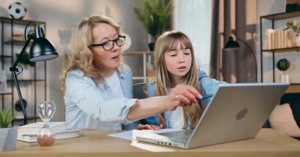 Aantrekkelijke emotionele verzorgende blonde moeder ruzie met haar slimme in staat tiener dochter tijdens het doen van schooltaken op het werk in de voorkant van de computer thuis, front view — Stockvideo