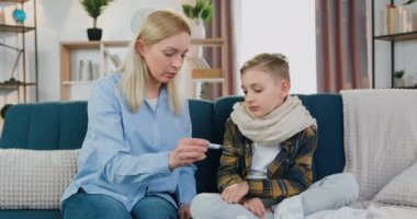 Güzel, sakin, şefkatli bir anne, üzgün, hasta oğluyla konuşurken vücut sıcaklığını termometreyle ölçtüğünde, yüksek göstergeleri gördüğünde, kapat.
