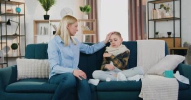 Sevecen anne, termometr ve sağlık hizmetleri kavramında yüksek göstergeler görünce titreyen, gripli, bitkin oğlunun ateşini kontrol ediyor.