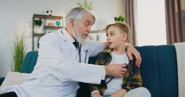 Médecins concept de visite à domicile où sympathique confiant sympathique médecin respecté hautement qualifié examinant les patients garçons respirent à l'aide stéthoscope, vue de face, au ralenti — Video