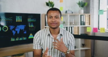 Çekici özgüvenli yaratıcı başarılı Afrikalı Amerikalı adam internet izleyicileri için videvlog kaydediyor modern ofis, ön görüş, yavaş çekim