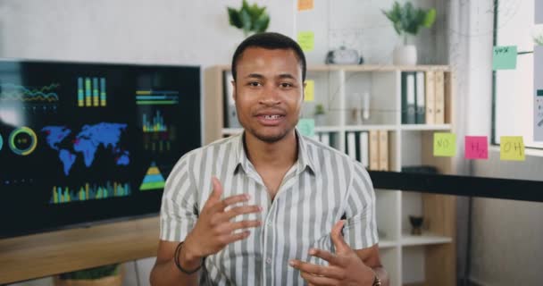 Camera weergave op sympathieke glimlachen tevreden succesvolle geschoolde Afrikaanse Amerikaanse office manager die video opnemen voor internet toeschouwers met duimen omhoog en applaus in moderne kantoorruimte — Stockvideo