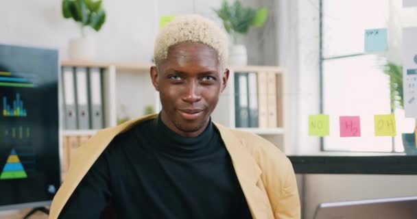 Sorrindo provável confiante jovem afro-americano com cabelo claro usa desgaste elegante posando na câmera no escritório moderno durante o dia, vista frontal — Vídeo de Stock