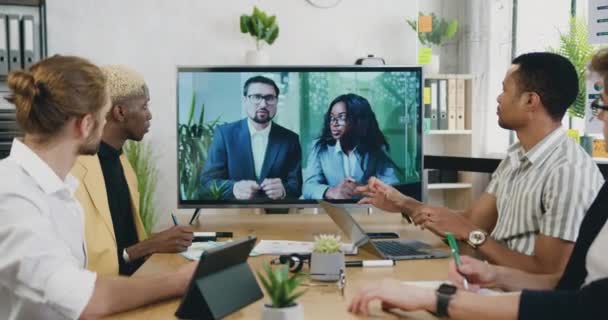 Vzdálený pracovní koncept, kde dobře vypadající pozorný zkušený různorodý mužské spolupracovníky pořádající videokonference v televizi z kanceláře s mezinárodními mužskými a ženskými kolegy — Stock video
