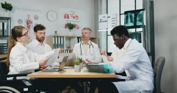 Medicinsk koncept där snygg säker kvalificerad meningsfull mångsidig team av läkare bekanta sig med rapporter under gemensamma möte på kliniken kontor — Stockvideo