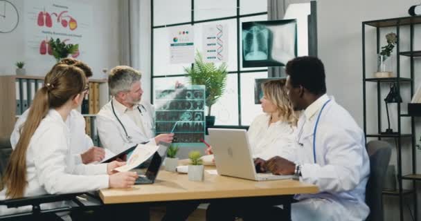 Medical council concept where good-looking confident qualified diverse medical workers discussing results of patients x-ray scan and advicing about further treatment — Stock Video