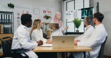 Güzel, kendine güvenen, tesettürlü Arap kadın doktor klinikteki toplantı sırasında uzman meslektaşlarına DNA yapısı hakkında bilgi veriyor.