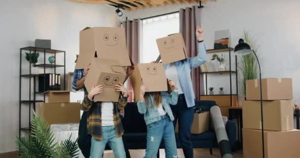 Atraente feliz alegre família amigável com caixas de rosto se divertindo juntos em nova casa, eles dançando e tirando suas caixas de cabeças — Vídeo de Stock