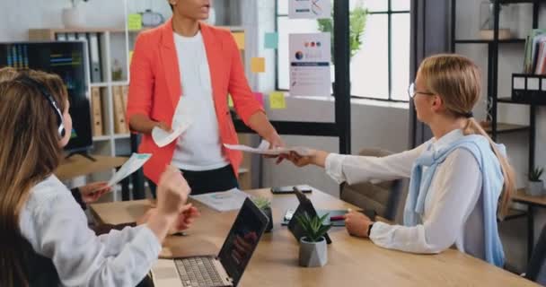 Erfolgreiche junge afrikanisch-amerikanische Frauen, überprüfen Forschungsberichte über das Papiermarketing, diskutieren Wachstumsstrategie mit verschiedenen kaukasischen Unternehmerinnen am Briefingtisch im Büro — Stockvideo