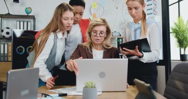 Разнообразная команда женщин-офисных работников обсуждает новые проекты и проводит мозговой штурм во время совместной работы на рабочем месте с ноутбуком в офисе — стоковое видео