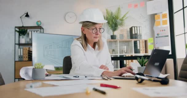 Mérnöki iroda koncepció, ahol elég magabiztos képzett felelős felnőtt női építész keménykalapban dolgozik számítógépes információk és tervrajz — Stock videók