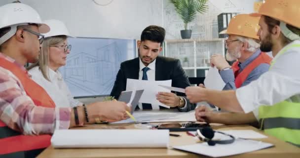 Flux de travail dans le bureau de conception où l'entrepreneur barbu compétent attrayant obtenir des rapports de professionnels responsables équipe diversifiée de spécialistes de la construction — Video