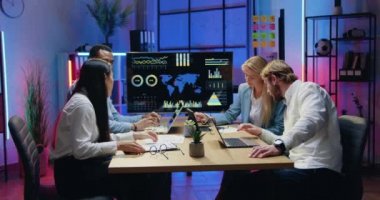 Çekici, kendine güvenen, çalışkan, çeşitli gençlerin modern akşam ofislerinde iş yerinde oturup bilgisayarlardan bilgi aldıkları bir iş konsepti.