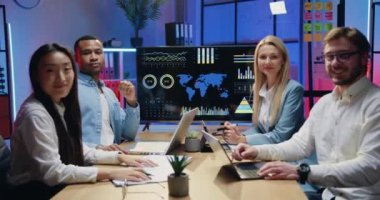 Çekici gülümseyen, kendine güvenen, yetenekli, genç ve çeşitli iş arkadaşlarının iş portresi. Akşam ofisinde poz veriyorlar.