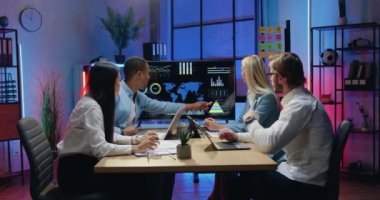 Çekici kendine güvenen çeşitli erkek ve kadın uzmanlar dünya ekonomik göstergelerini tartışırken ofiste fazla mesai sırasında dijital ekranda eksildi