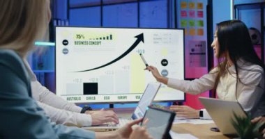 Çekici, kendine güvenen, yetenekli çeşitli iş arkadaşları akşamları modern ofiste işyerinde oturup dijital ekran üzerindeki araştırma verilerini kullanarak ortak iş konseptini tartışıyorlar.