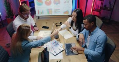 İyi görünümlü profesyonel deneyimli erkek ve kadınlar akşam ofisinde başarılı bir şekilde çalıştıktan sonra birbirlerini el sıkışarak selamlıyorlar.