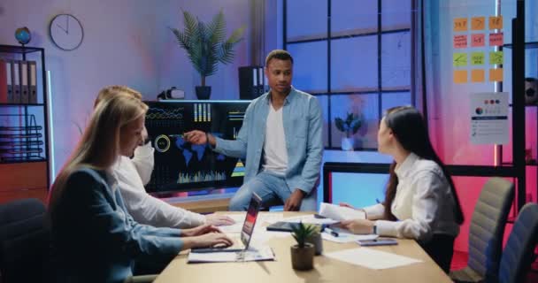 Workflow ve večerní kanceláři, kde atraktivní sebevědomý zodpovědný kvalifikovaný afroameričan muž manažer vysvětlující prezentaci na digitální obrazovce pro pozorný motivovaný rozmanitý tým spolupracovníků — Stock video