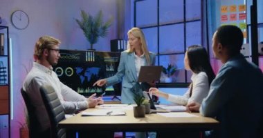 İyi görünümlü kendine güvenen yüksek yetenekli analitik ekibi, akşam saatlerinde dijital monitörde harita kullanarak dünya istatistik göstergelerini analiz ediyor.