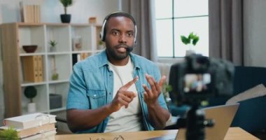 İyi görünümlü, kendine güvenen, sakallı, Afro-Amerikan bir adam. Kulaklıklı. İnternet izleyicileri için yeni video kaydediyor.