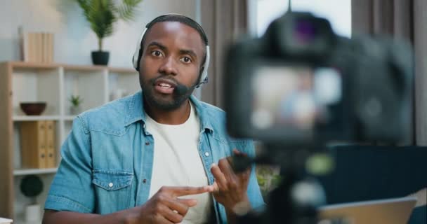 Close up of handsome concentrated professional bearded african american blogger in headset which sitting in front of camera at home during filming new video for his internet vlog — Stock Video